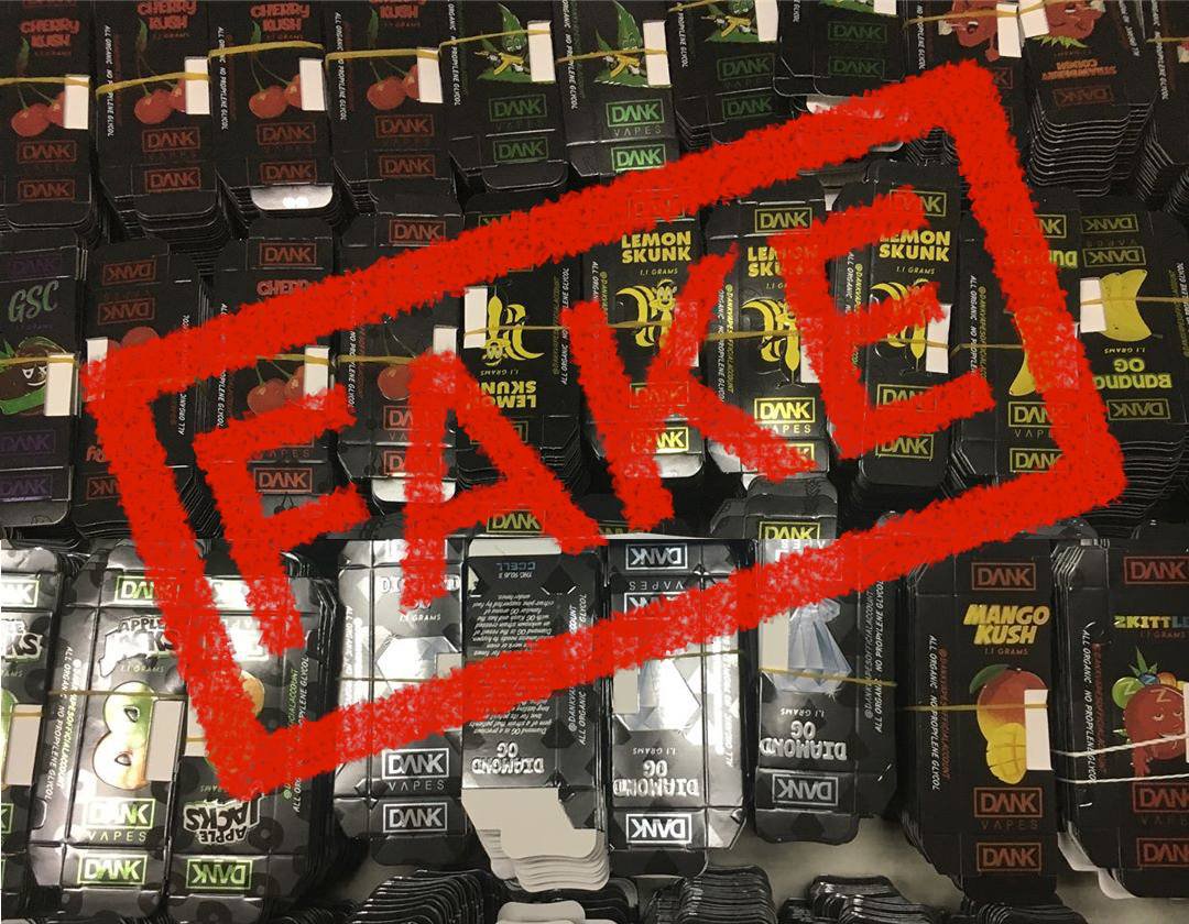 gloved hands holding a thc cartridges with the word fake stamped on top of the image in large red font