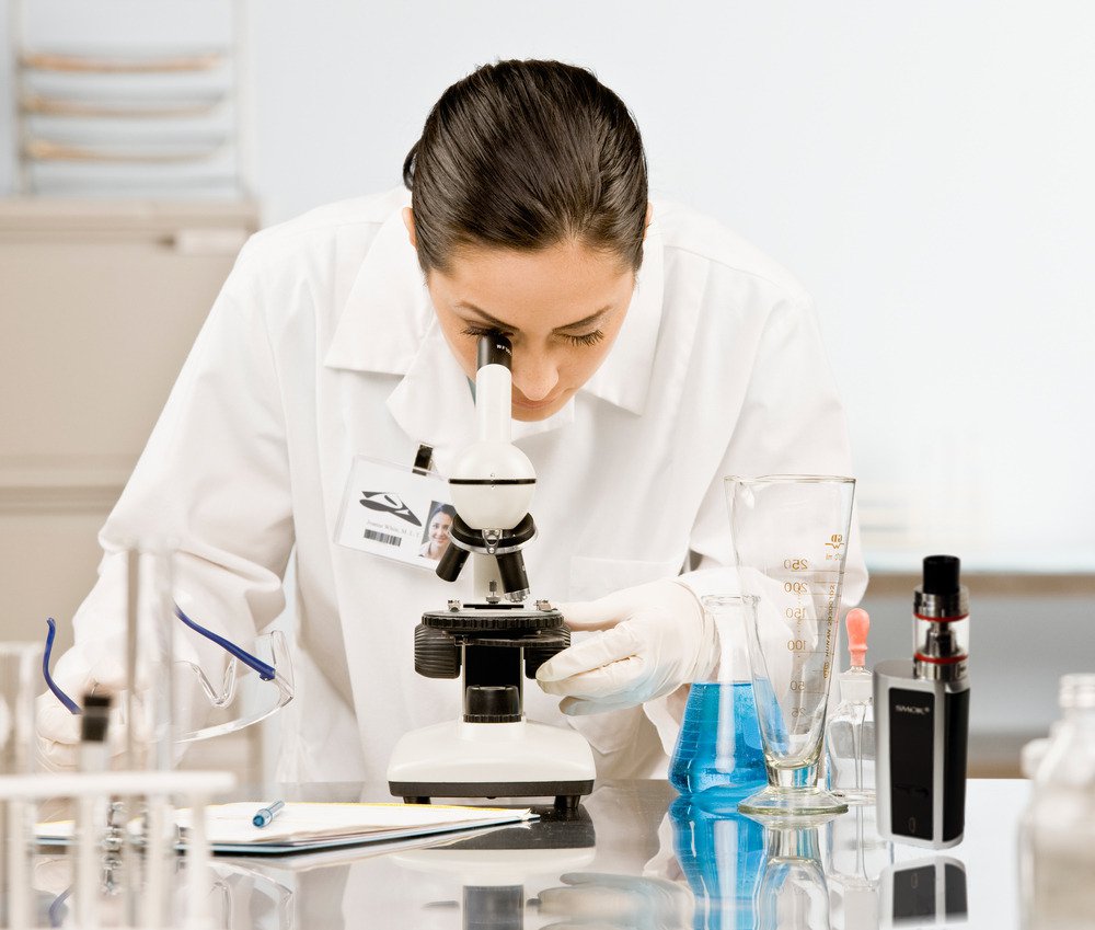 Female scientist looking at microscope with vape on desk (photoshop)